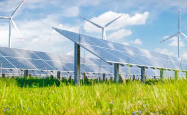 Renewable energy landscape with bright sunshine, solar panels and wind turbines