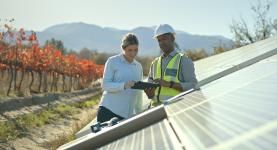 Two people talking next to solar panels