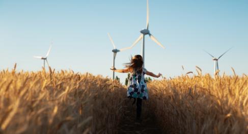 Girl running towards wind farm
